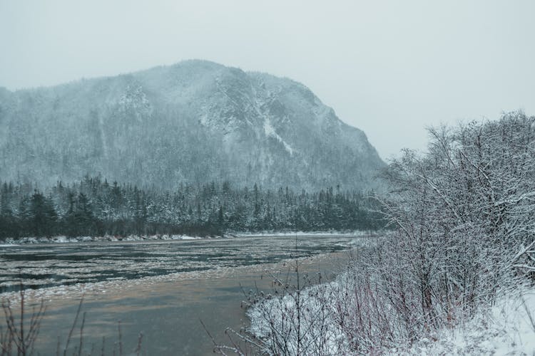 Scenery Of River And Snowy Mountains Under Cloudy Sky In Winter Time