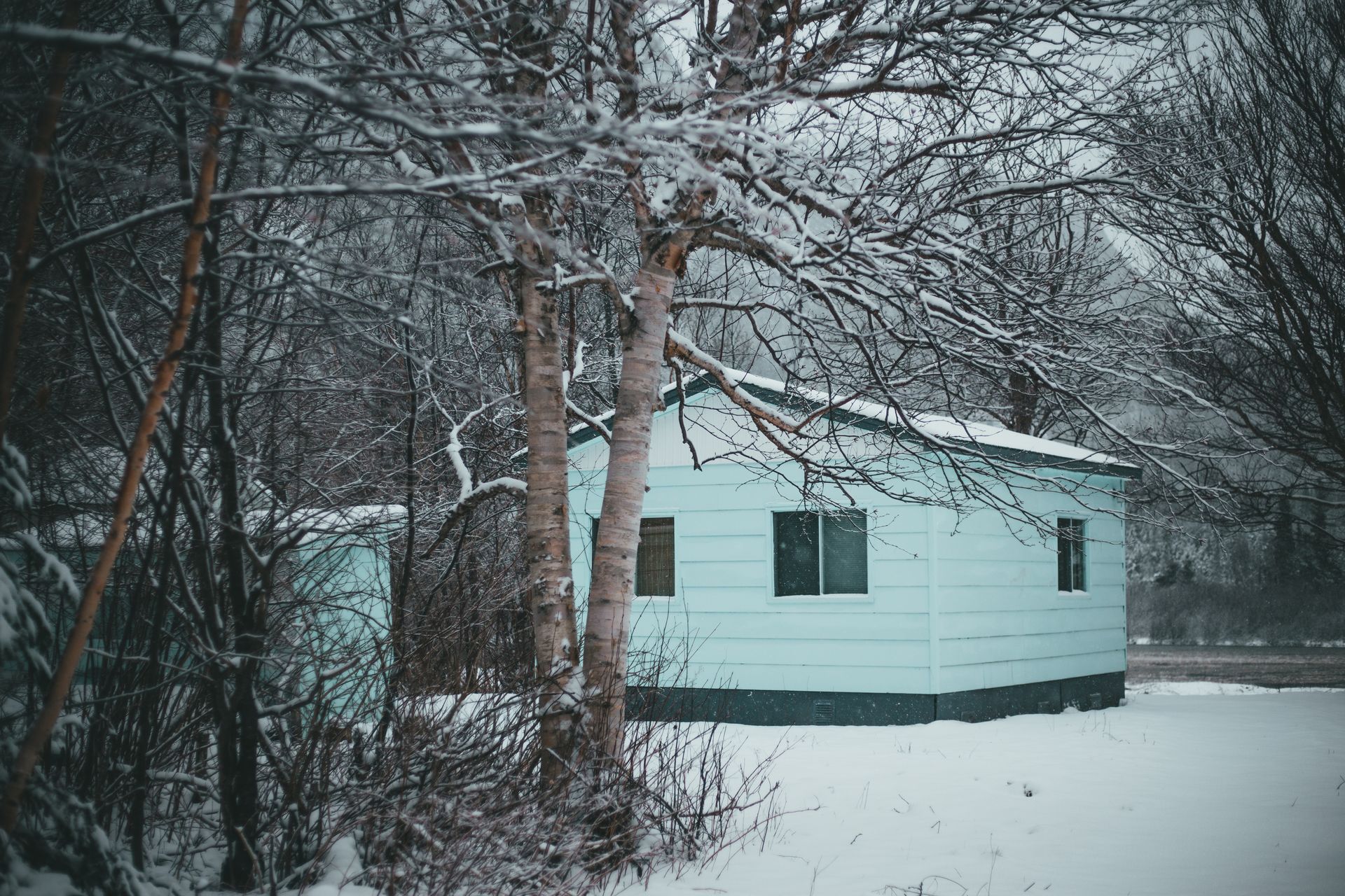 Exterior design of wooden cabin house with square windows and mint walls with snow on roof