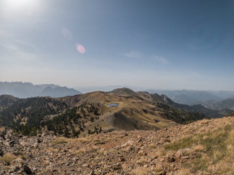 Stunning aerial view of Drakolimni Lake in Greece surrounded by rocky mountains and a blue sky.