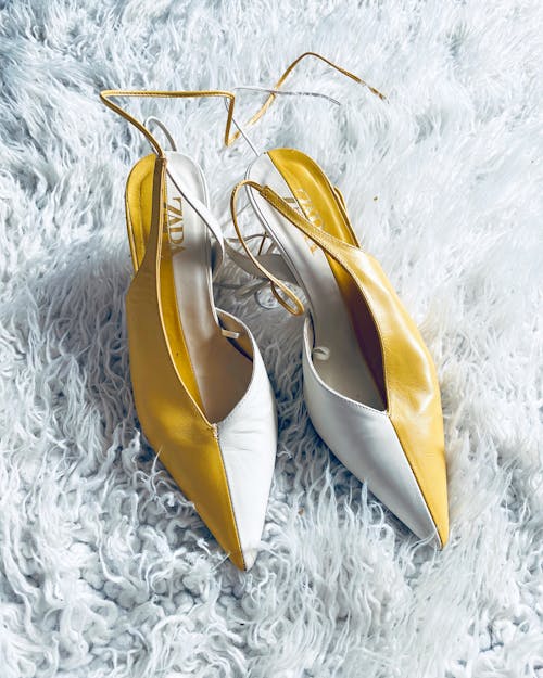 Free Pair of Yellow aand White Leather Ankle Strap Heels Pumps on White Fur Textile Stock Photo