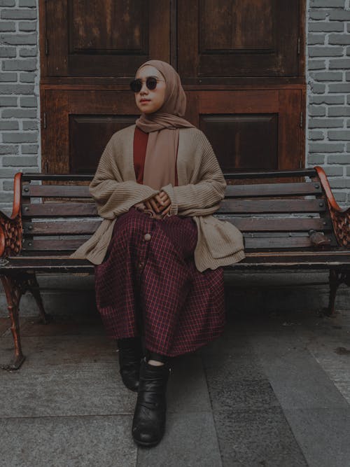Free Woman in Brown Cardigan Sitting on Brown Wooden Bench Stock Photo
