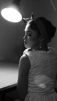 Artistic black and white portrait of a young woman with a retro headband in dramatic lighting.