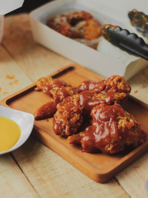 Free Close-up of crispy fried chicken with sauce served on a wooden platter, perfect for meal inspiration. Stock Photo