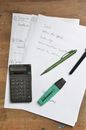 Calculator and stationary on paper sheets on table