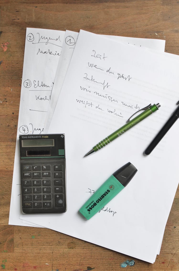 Calculator And Stationary On Paper Sheets On Table