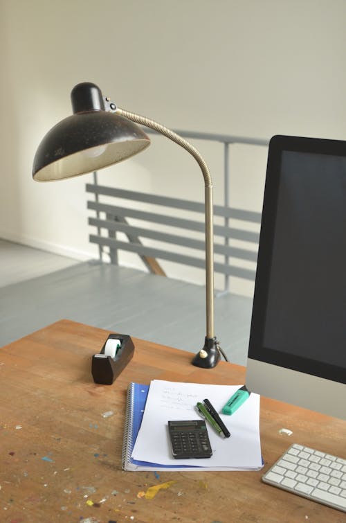 High angle of wooden table with Monitor and keyboard lamp papers and office supplies on workplace