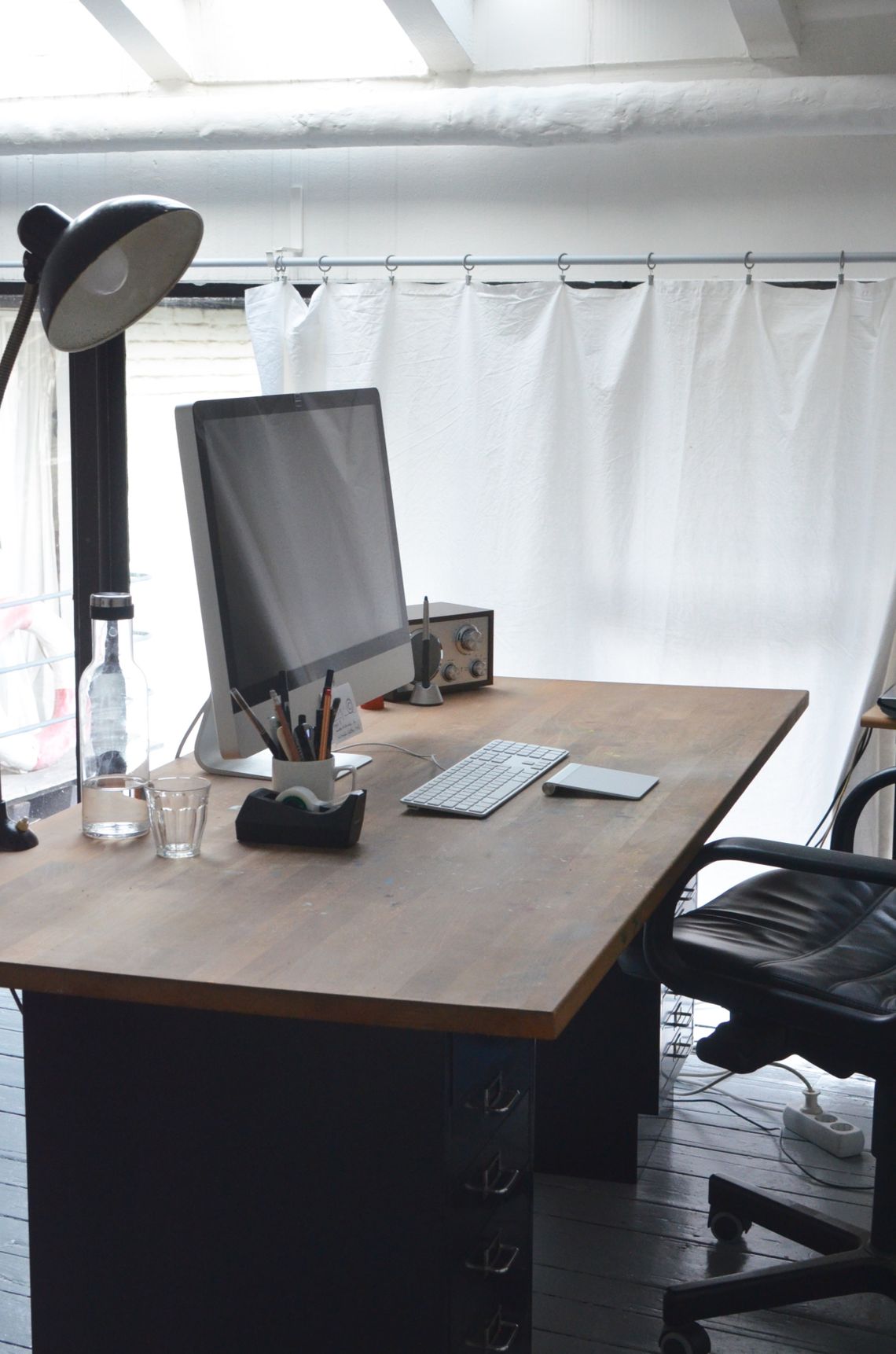 Minimalist office desk with computer, keyboard, lamp and modern chair