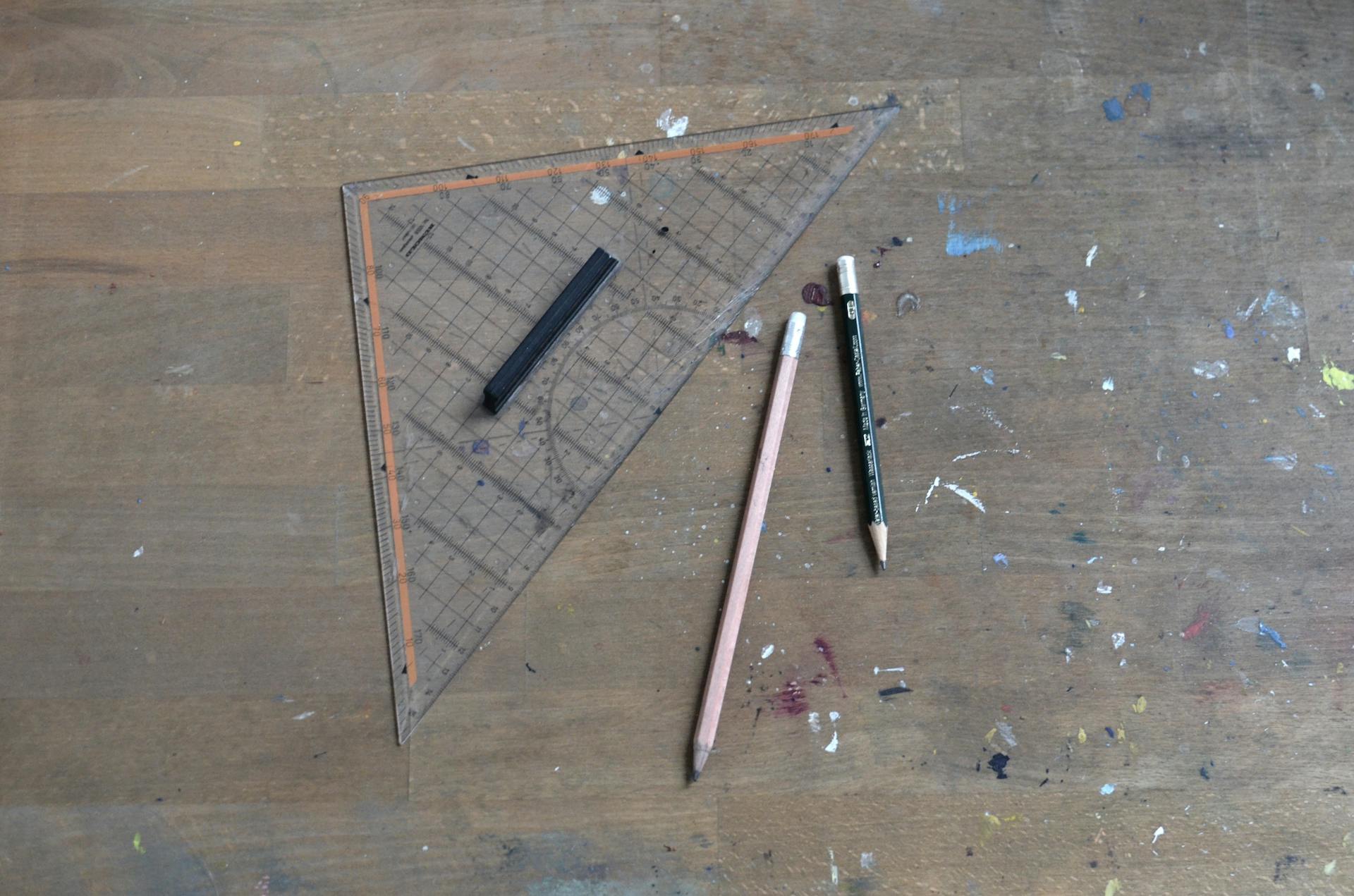 A wooden workspace featuring drafting tools such as a triangle ruler and pencils for creative projects.