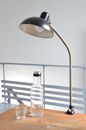 Old fashioned lamp with glass and bottle of water placed on wooden table