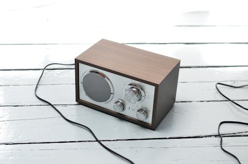 From above of vintage styled FM radio with wooden case and steel buttons placed on white lumber table