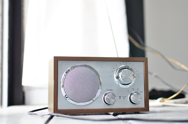 Classic styled radio receiver with chrome buttons and speaker and wooden case placed on table in daylight
