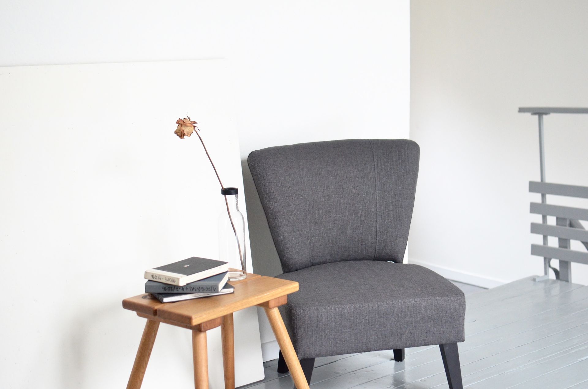 Cozy reading nook featuring a grey armchair, wooden table, and books in a minimalist interior.