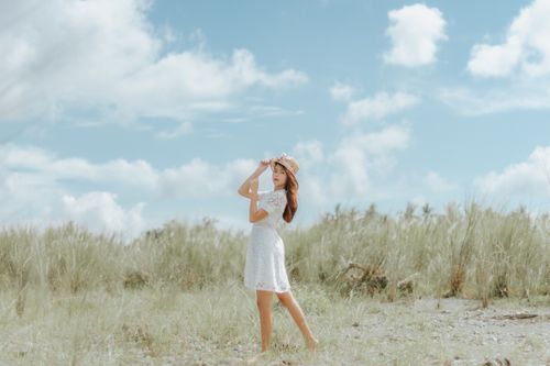 Free Side view full body of barefoot ethnic female standing in graceful posture in grassy meadow and looking at camera Stock Photo