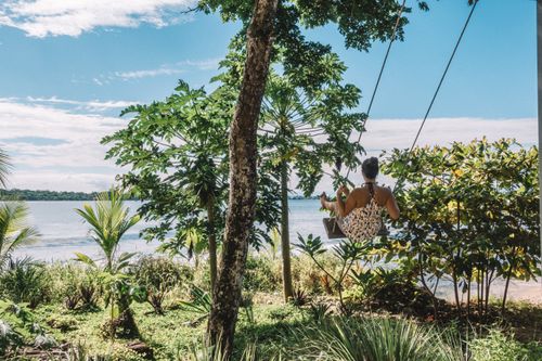 Free A woman enjoys a swing by the beach, surrounded by lush tropical greenery, capturing the essence of tranquility in Panama. Stock Photo