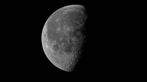 Black and white surface of moon with craters with dark side on night sky