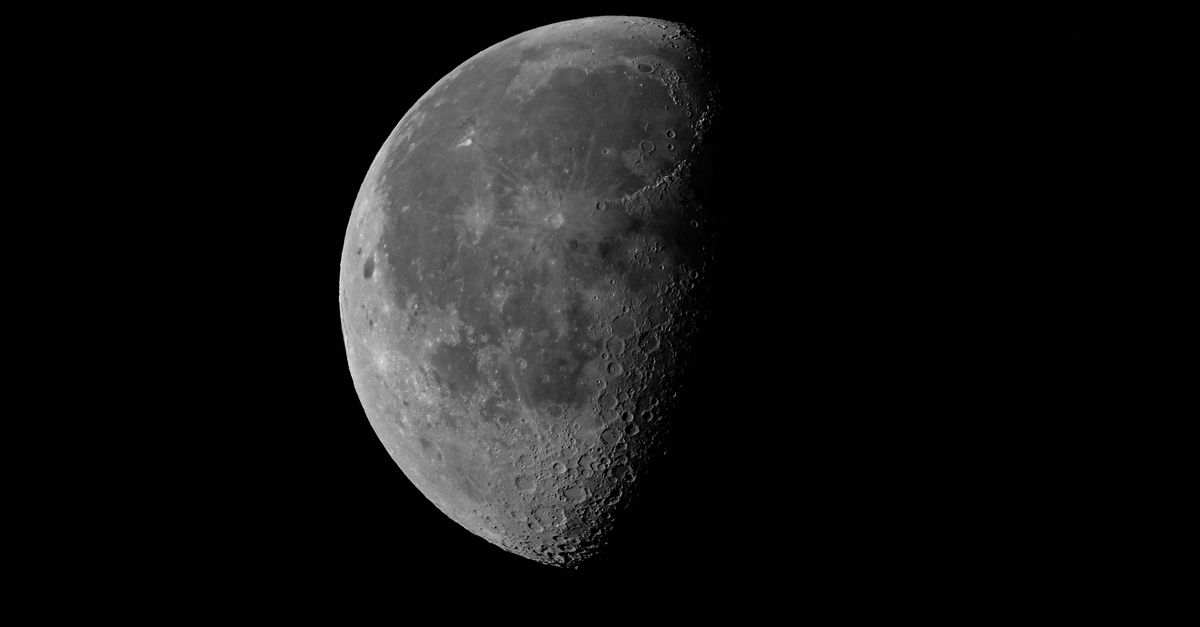 Black and white surface of moon with craters with dark side on night sky