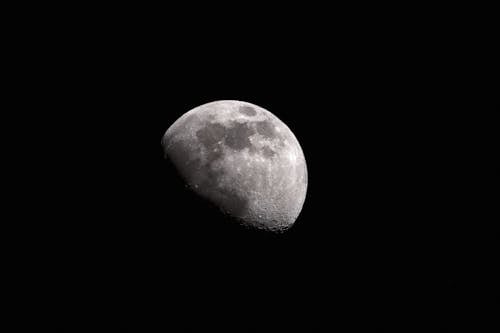 Black and white of moon with craters glowing on black sky at night