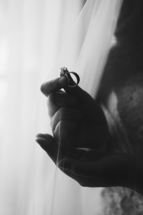 Free Black and white close-up of a hand holding a wedding ring behind a veil. Stock Photo