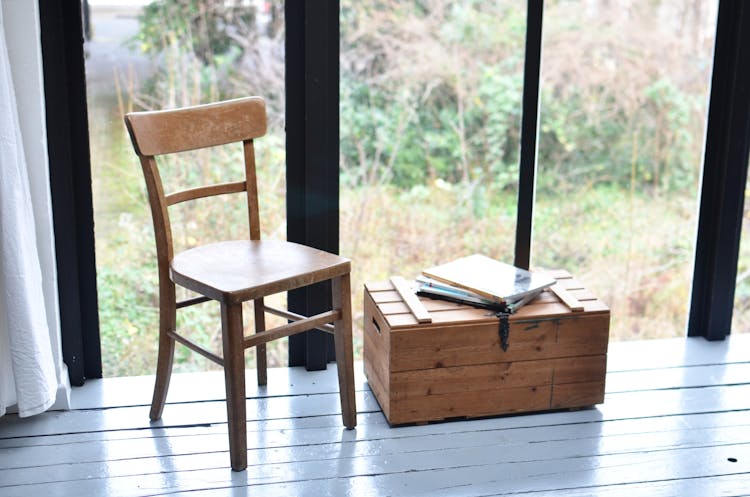 Wooden Chair Near Vintage Chest Against Window