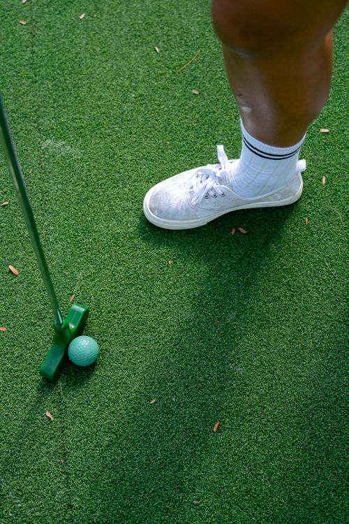 Free A golfer preparing to putt on green artificial turf with a turquoise golf ball. Stock Photo