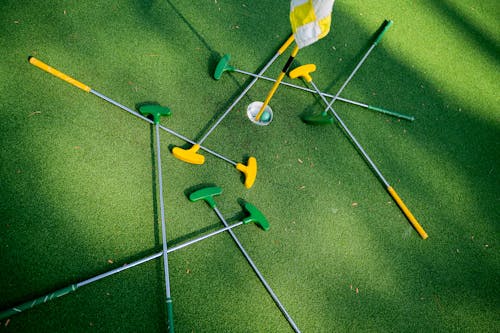 Scattered Green and Yellow Putters on Green Grass