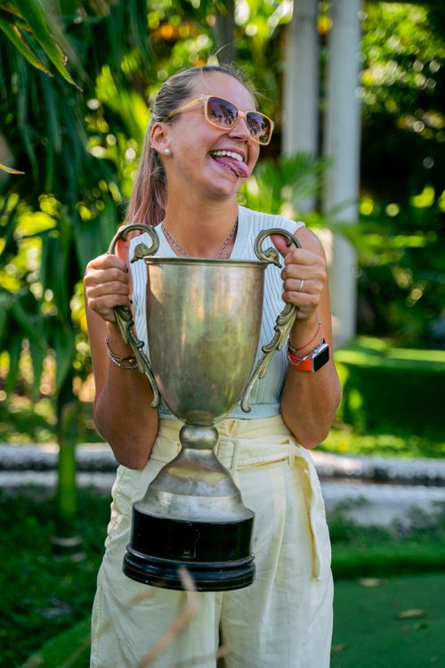 Free A joyful woman proudly holding a trophy in a lush outdoor setting. Stock Photo