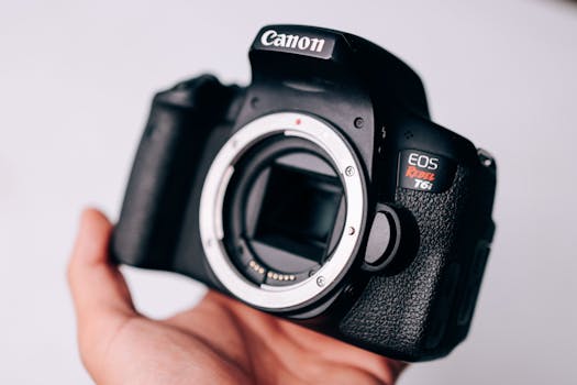 A detailed close-up of a DSLR camera held in a person's hand, showcasing electronic features.