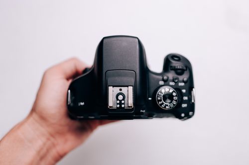 Free A handheld DSLR camera showing control dials and buttons, isolated on a white background. Stock Photo