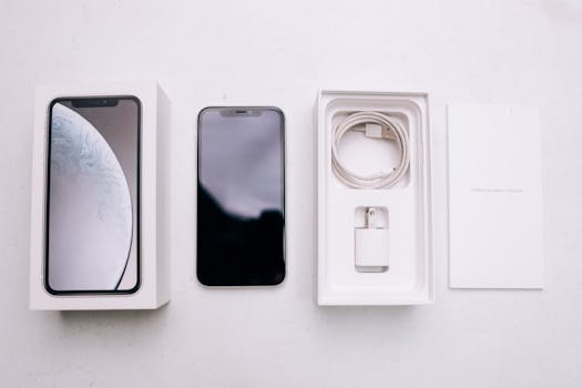 A neatly arranged flatlay of a smartphone with its packaging and accessories on a white background.