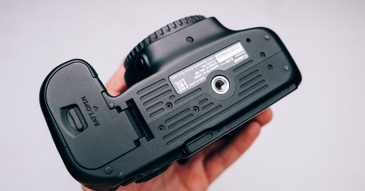 Close-up view of a camera held in a hand, displaying the bottom part.