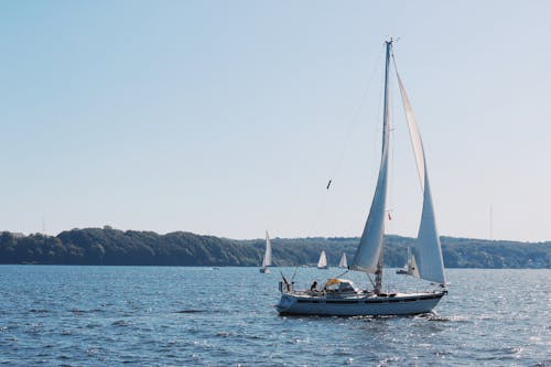 Free A Person Sailing on a White Sail Boat in the  Sea Stock Photo