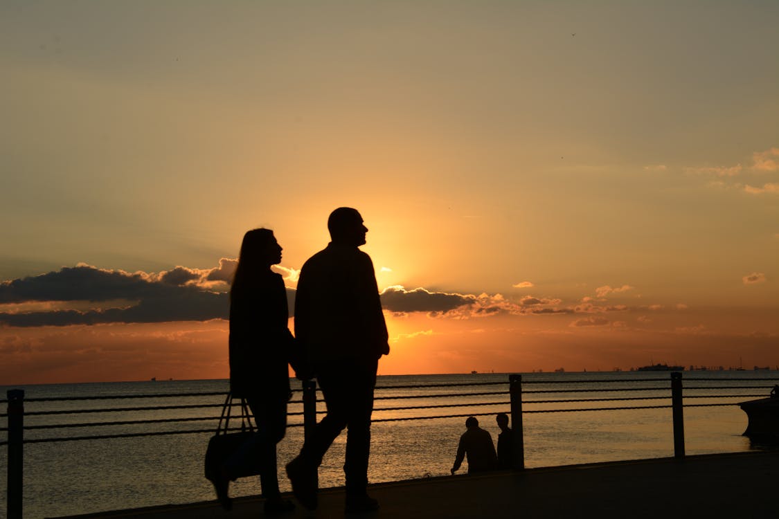 gratis Man En Vrouw Silhouet Wandelen Tijdens Zonsondergang Stockfoto