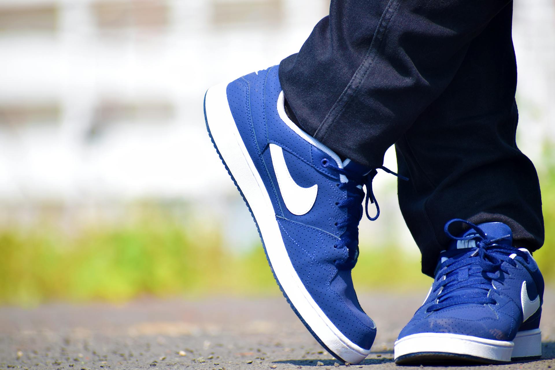 Blue Nike sneakers worn by adult on outdoor pavement, showcasing urban street fashion.