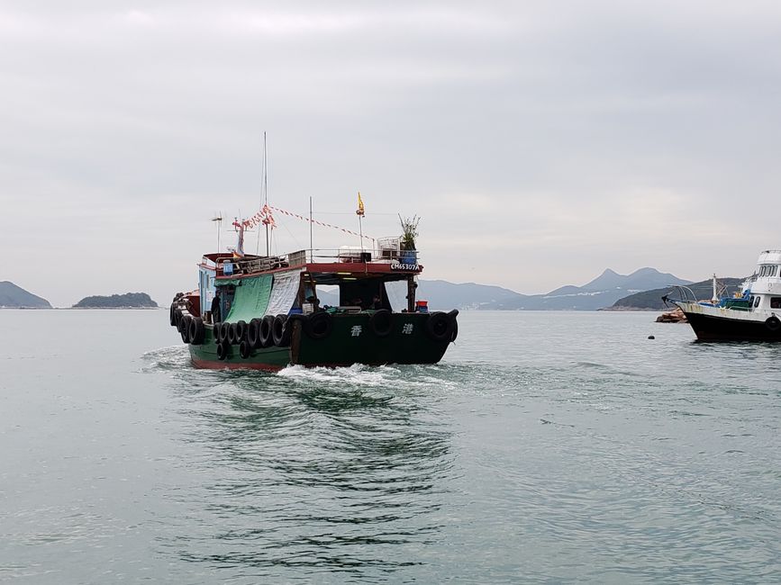 A traditional wooden fishing boat navigating the serene waters off Hong Kong.
