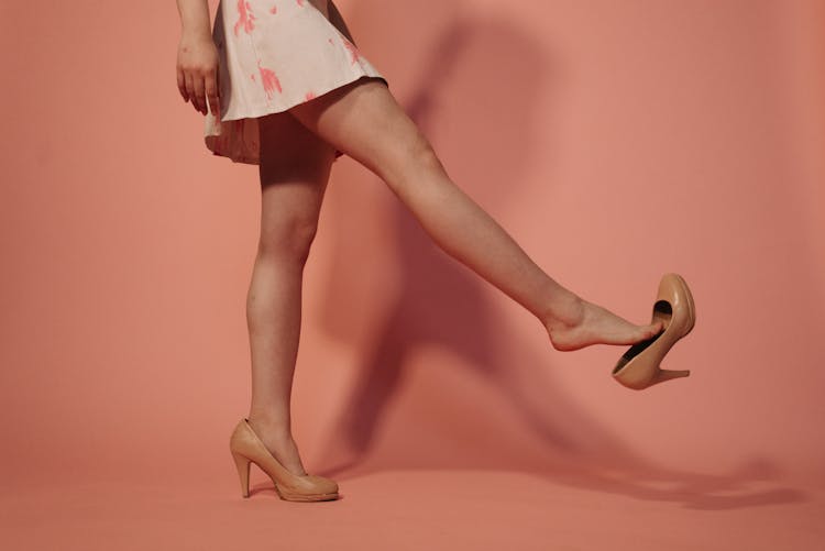 A Woman In White And Pink Dress Taking Her Shoe Off