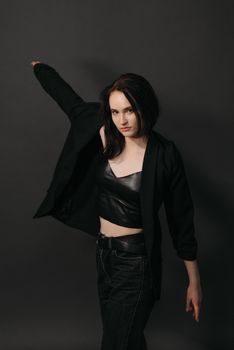 Stylish woman in black blazer and leather crop top striking a confident pose.