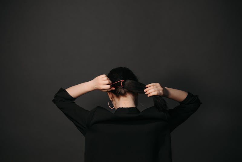 a woman tying her hair with a scrunchie