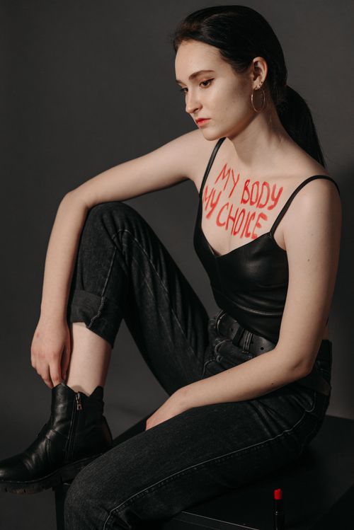 Free Caucasian woman in studio pose with empowering message 'My Body My Choice' written on her chest. Stock Photo