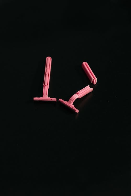 Free Close-up of three pink razors arranged on a black background. Stock Photo