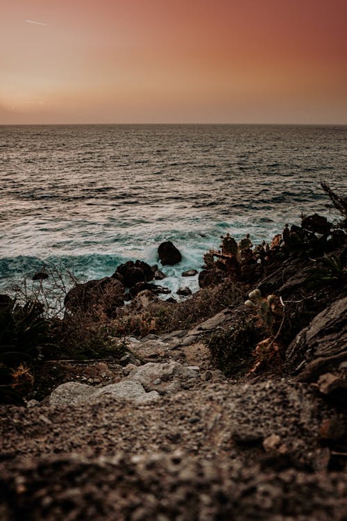 Brown Rocks on Sea Shore during Sunset