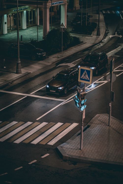 Free Overhead view of a city intersection at night, showcasing cars, traffic lights, and a crosswalk. Stock Photo