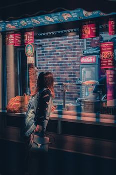 A woman orders at a street food vendor at night, capturing urban nightlife ambiance.