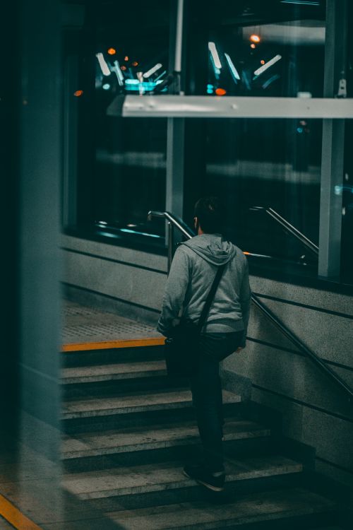 Free A person walks up stairs in a dimly lit subway station at night. Stock Photo