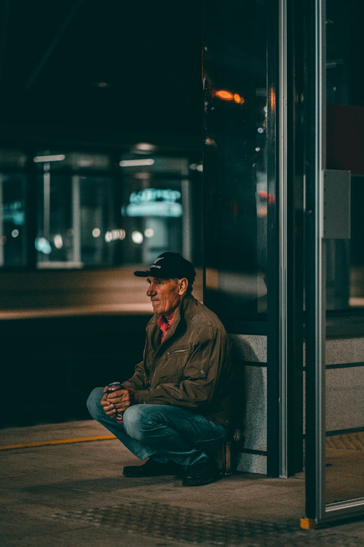 Senior Man Crouching On The Street At Night