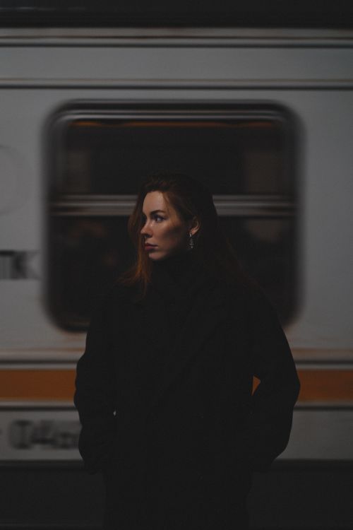 Free A woman posing in a night railway station against a moving train backdrop. Stock Photo