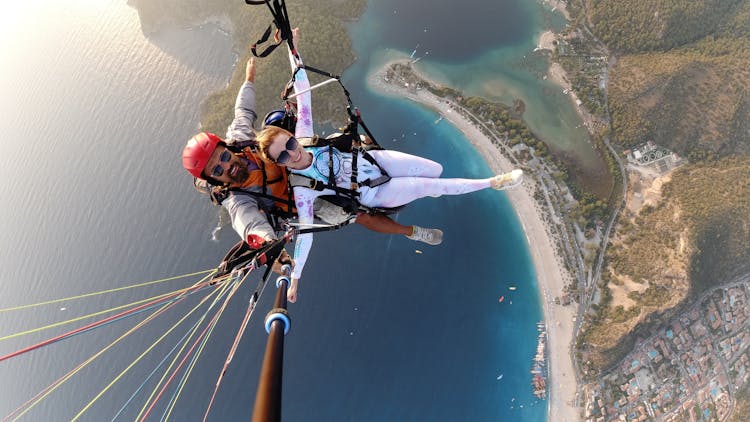 Overjoyed Couple On Parachute Above Water