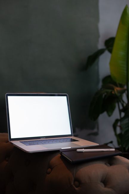 Fotomural Configuración contemporánea de espacio de trabajo con una laptop con pantalla en blanco y un cuaderno en un sofá.