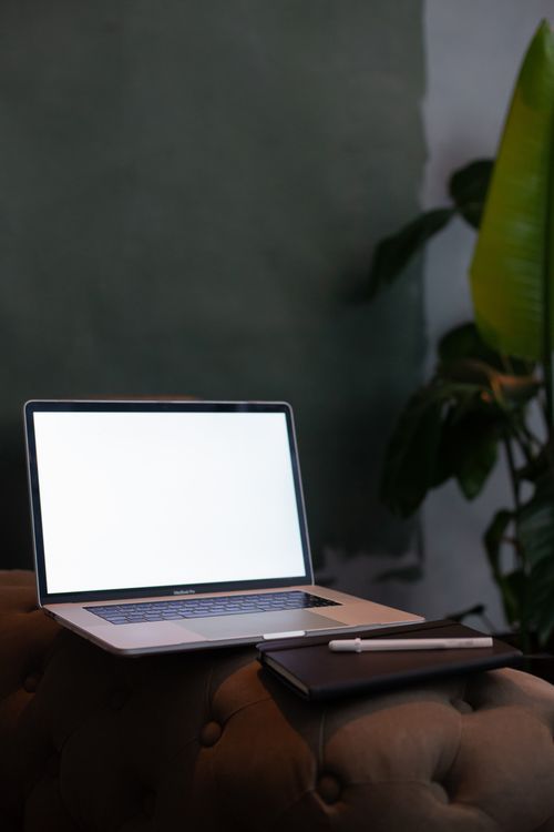 Free Contemporary workspace setup featuring a laptop with blank screen and a notebook on a couch. Stock Photo