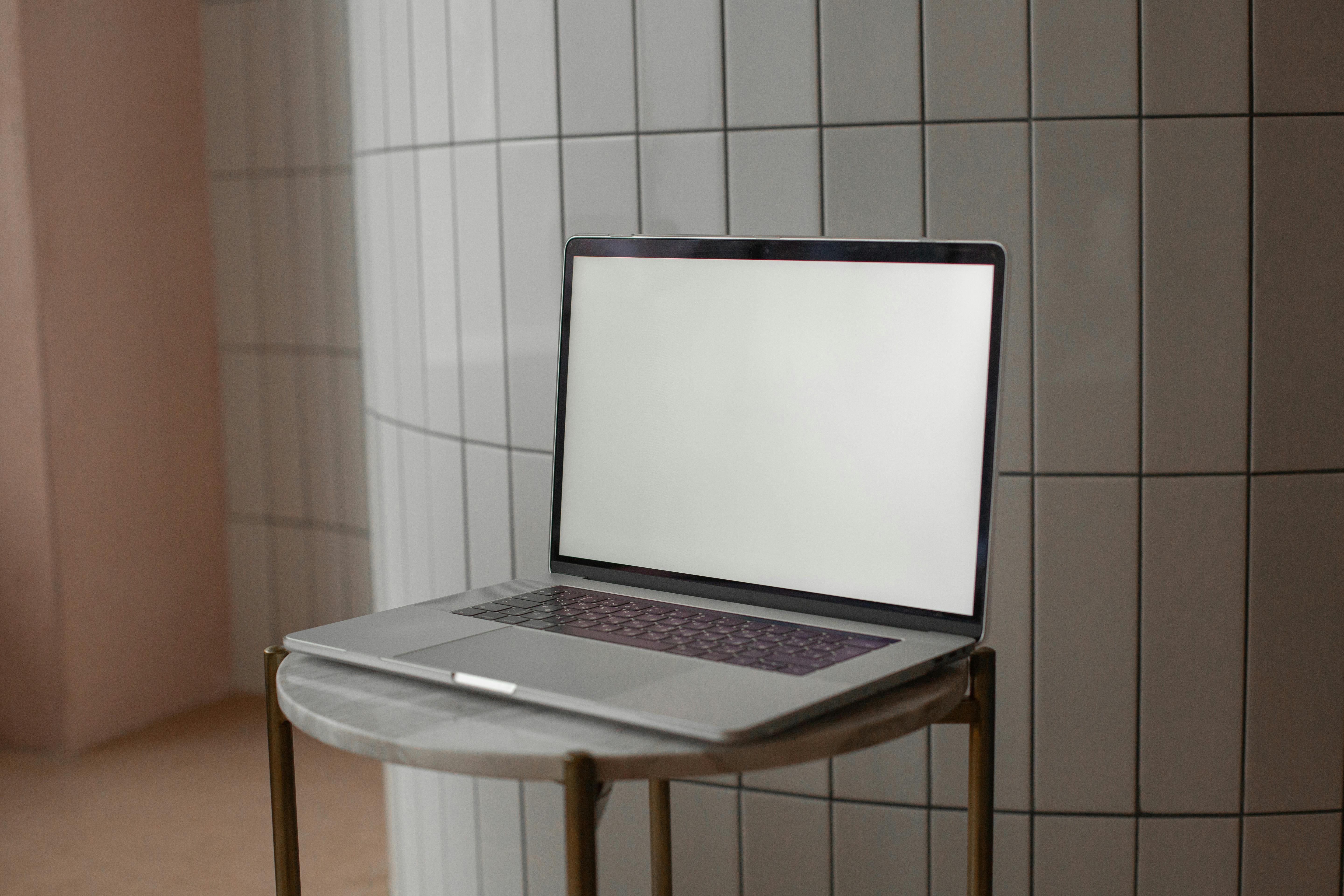 A sleek laptop with a blank screen on a round marble-top table indoors.