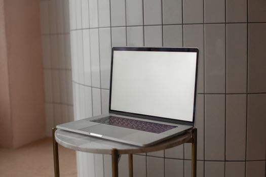 A sleek laptop with a blank screen on a round marble-top table indoors.